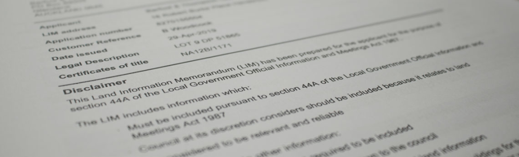 一個人正在用放大鏡仔細研究一份關於紐西蘭房地產買賣的LIM報告文件。